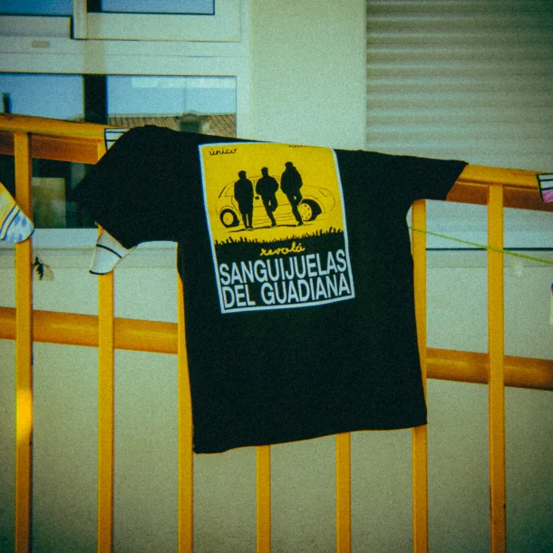 Camiseta negra de Sanguijuelas del Guadiana tendida sobre una barandilla amarilla